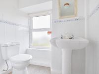 Baño blanco con aseo y lavamanos en Finest Retreats - West Cottage at Goldsithney, en Perranuthnoe