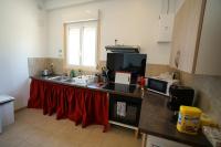 a kitchen with a sink and a counter with a red curtain at Camping Arbre de Vie in Montagnac
