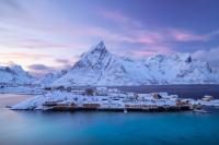 una ciudad en medio del agua con montañas cubiertas de nieve en Sakrisøy Rorbuer, en Reine