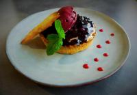 ein Donut auf einem weißen Teller mit einem grünen Blatt in der Unterkunft Logis Hôtel Volcan Sancy in Nébouzat