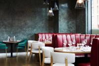a restaurant with tables and chairs and red booths at Hyatt House Manchester - Aparthotel in Manchester