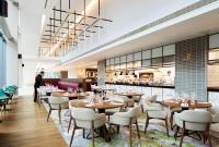 a restaurant with tables and chairs and a chef in the background at Hyatt House Manchester - Aparthotel in Manchester