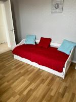a bed with a red blanket and two pillows on it at appartement spacieux et lumineux proche de la plage in Quimiac
