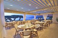 a restaurant with tables and chairs and a view of the ocean at Hotel Tettola in Saint-Florent