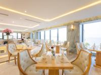 a restaurant with tables and chairs and large windows at Canary Gold Hotel Quy Nhơn - Beachfront - Iconic Location in Quy Nhon