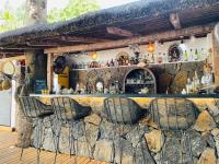 Un bar con tres sillas frente a una pared de piedra. en Cosy Guest House Sous le Badamier, en Grand Baie