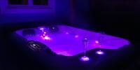 a purple bathtub with two wine glasses and lights at Adorable chalet avec jacuzzi privatif in Aix-en-Provence