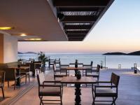 a restaurant with tables and chairs and a view of the ocean at NIKO Seaside Resort MGallery in Agios Nikolaos