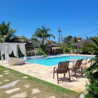 a swimming pool with chairs and a table next to it at Pousada Casa do Catavento in Búzios