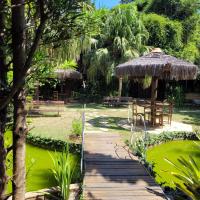 a wooden path leading to a garden with a table and chairs at Pousada Casa do Catavento in Búzios