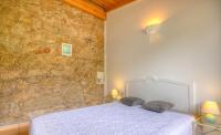 a bedroom with a white bed and a stone wall at Gîte à Piscia de Figari Petru Barbara in Figari