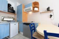 a small kitchen with blue cabinets and a table and chairs at 1 bedroom apartment in a residence with a swimming pool and a parking spot in Vallauris