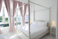 a white bedroom with a white canopy bed and windows at Milk White Homestay in Hengchun South Gate