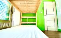 a bedroom with a white bed and a green wall at 澎湖北吉光背包客民宿 Bayhouse Hostel Penghu in Magong