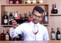 a man pouring a bottle of wine into a wine glass at Hotel New Era in Kathmandu