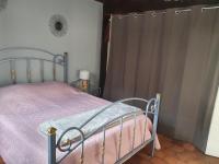 a bedroom with a bed with a pink blanket and curtains at Gite les Bruyères in Salbris
