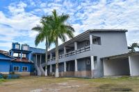 a palm tree in front of a white building at Hotel Marina Clube de Pesca in Cananéia