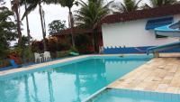 a swimming pool with blue water and palm trees at Hotel Marina Clube de Pesca in Cananéia