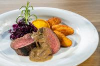 un plato de comida con carne y patatas en una mesa en Gasthof Kleefeld, en Strobl