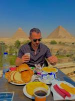 un hombre sentado en una mesa con un plato de comida en Sahara Pyramids Inn, en El Cairo