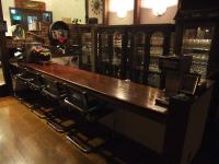 a bar in a pub with a long wooden counter at Guesthouse Sakuya in Fujikawaguchiko