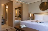 a bedroom with a large white bed and a bathroom at Jumeirah Muscat Bay Oman in Muscat