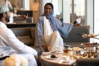 a woman sitting on a couch in a restaurant at Jumeirah Muscat Bay Oman in Muscat