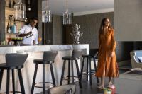 a woman standing in front of a bar with a man at Jumeirah Muscat Bay Oman in Muscat