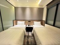 two beds in a room with a table and two windows at Hotel Midtown Richardson in Taipei