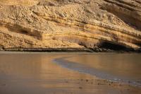 a beach with a cave in the side of a cliff at Jumeirah Muscat Bay Oman in Muscat