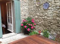 a stone wall with a table and flowers next to a building at La Maison de la Riviere B&amp;B in Espéraza