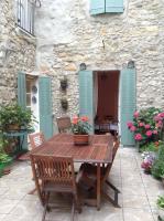 a wooden table and chairs in front of a stone building at La Maison de la Riviere B&amp;B in Espéraza