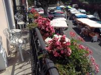 a balcony with tables and flowers on a street at La Maison de la Riviere B&amp;B in Espéraza