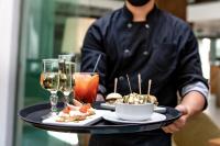 Un camarero sosteniendo una bandeja con comida y bebidas. en Caseros 248 Hotel, en Córdoba