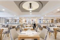 a man standing in a dining room with tables and chairs at Hotel Riu Madeira - All Inclusive in Caniço