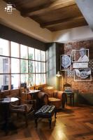 Una sala de estar con un sofá, mesas y ventanas. en Roots Chew Hotel, en Tainan