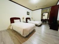 a hotel room with two beds and a television at Abbo Hotel in Tainan