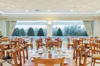 Un comedor con mesas y sillas y grandes ventanales. en Akti Taygetos - Conference Resort, en Kalamata