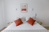a white bed with two orange pillows on it at Hôtel Porte Mars Reims Gare Centre Arena in Reims