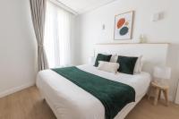 a white bedroom with a large bed with a green blanket at Hôtel Porte Mars Reims Gare Centre Arena in Reims