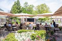 un grupo de personas sentadas en mesas bajo sombrillas en un jardín en Château Brachet, en Grésy-sur-Aix