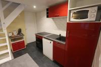 a small kitchen with red cabinets and a microwave at Apparts Gites Cholet centre in Cholet