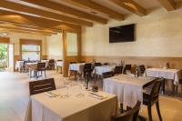un restaurante con mesas y sillas blancas y TV en Hotel Alta Garrotxa, en Tortellà