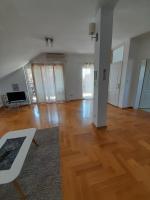 an empty living room with wooden floors and windows at Apartment Ken in Surčin