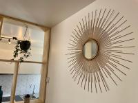 a sunburst mirror on the wall in a bathroom at Le Cosy in Bayeux