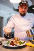 uno chef che prepara un piatto di cibo su un tavolo di Apartamenty w Kamienicy a Sieradz