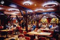 un grupo de personas sentadas en mesas en un restaurante en Western Camp Resort, en Zator