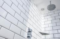 a white tiled bathroom with a shower at The Olde Malthouse Inn in Tintagel