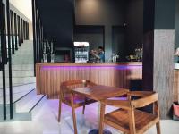 外南梦Onesouth Banyuwangi Pulau merah的一位女士站在吧台后面，吧台前摆放着一张木桌和几把椅子。