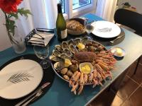 a table with a plate of seafood and a bottle of wine at Gîte cosy sur jardin in Moëlan-sur-Mer